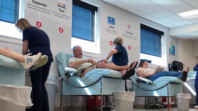 People lined up in chairs donating blood.