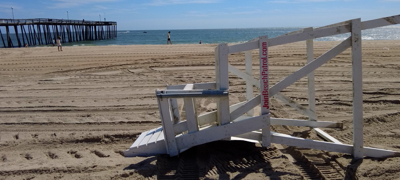 A white lifeguard stand laying on its side on the sand.