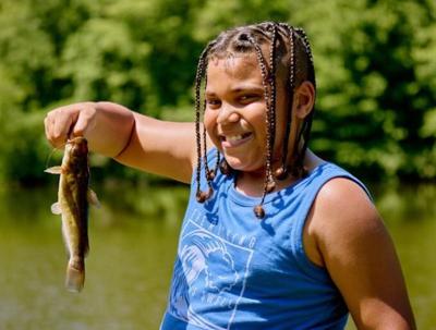 An image of a young child holding a small fish,