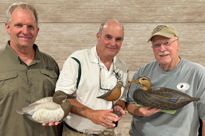 3 men pose for a photo holding decoy ducks 