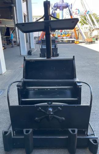 A car from a haunted mansion ride. The all black car has a skull and crossbones on the front.