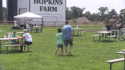 Children and parents walk around tables on a farm.