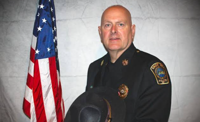 Andy McGee in his Snow Hill police uniform with American Flag to his left.