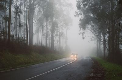 A car driving on a dark road with its lights on.