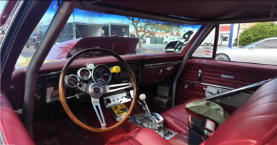 the interior of a car made before 2000 with a wood trim steering wheel and red leather seats.