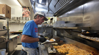 Line cook placing hashbrowns onto a plate. 