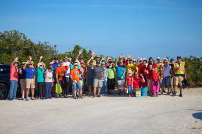 Volunteers group together for a photo in front of a beach dune.