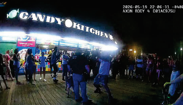 Several people surround a police officer and K-9 in front of the Candy Kitchen.
