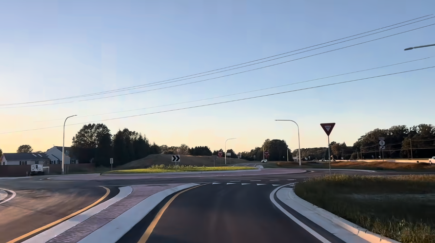 A picture from a drivers point of view with no cars in the roundabout.