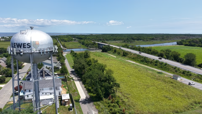 An aerial view of an open field between a highway and the Lewes water tower. 