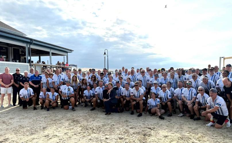 A group photo of the bicyclists on the sand.