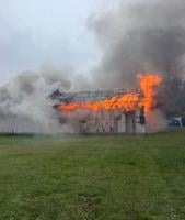 Flames coming out of the roof of the building surrounded by smoke.