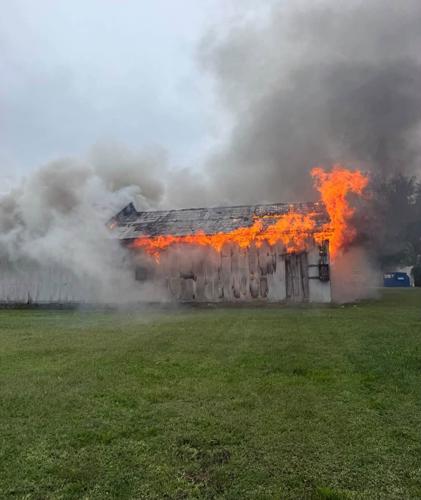 Flames coming out of the roof of the building surrounded by smoke.