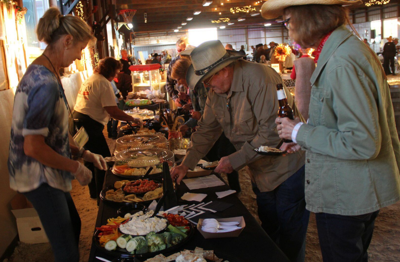 A woman serves food behind a table at a party.