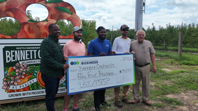 Five men hold up a check for the farm they are at.