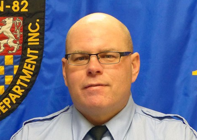 A headshot of Michael Truitt in front of the Lewes Fire Department logo.