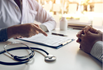 A medical professional in a white lab coat on the left pointing to chart in a clipboard.