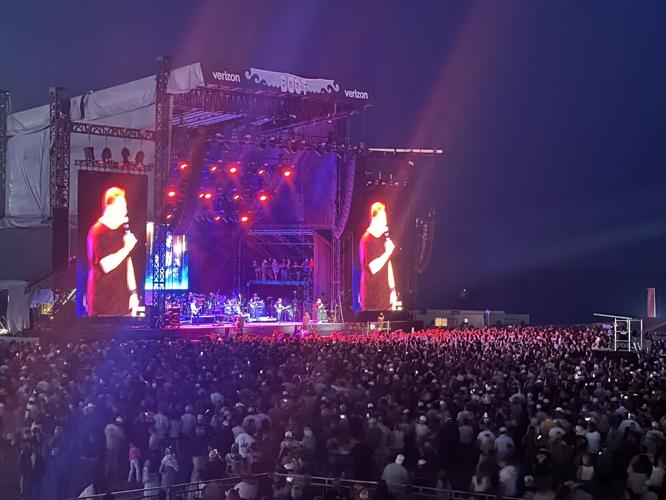 A crowd of people at night fill the area in front of the Boot Stage for Rascal Flatts.