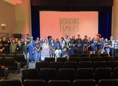 A large gathering on stage Wilmington's Theatre N with a banner in the back reading Working Families Party