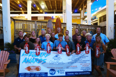 Several people stand with a banner and awards.