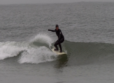A surfer in a body suit riding a wave.