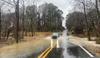 A car drives through a flooded Cave Neck Road Monday Dec 18