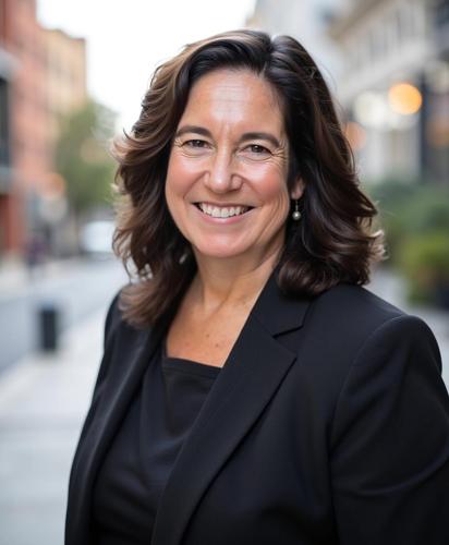 Women smiling in black blazer outside.