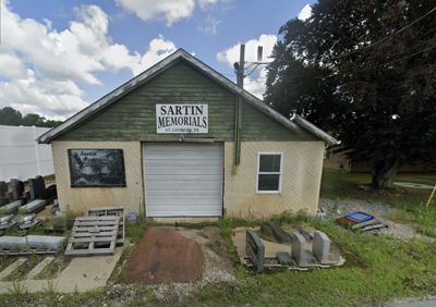Green building with yellow walls. Sign says "Sartin Memorials"