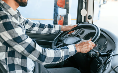 Man in black and white plaid shirt driving a tractor trailer