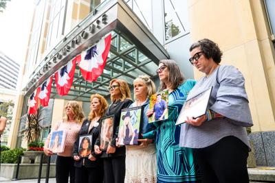 Women line up holding pictures of children.
