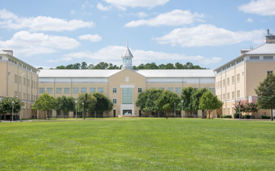 College building on a green yard, covered with trees on a sunny day. 