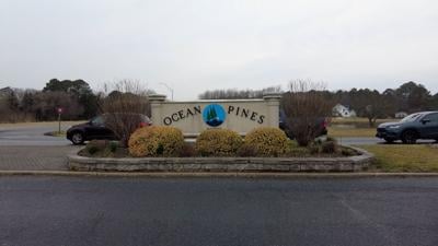 A sign that reads "Ocean Pines" in front of parking spaces.