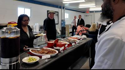 Inmates behind a table as people enjoy buffet style Thai cuisine that inmates prepared after graduating culinary program