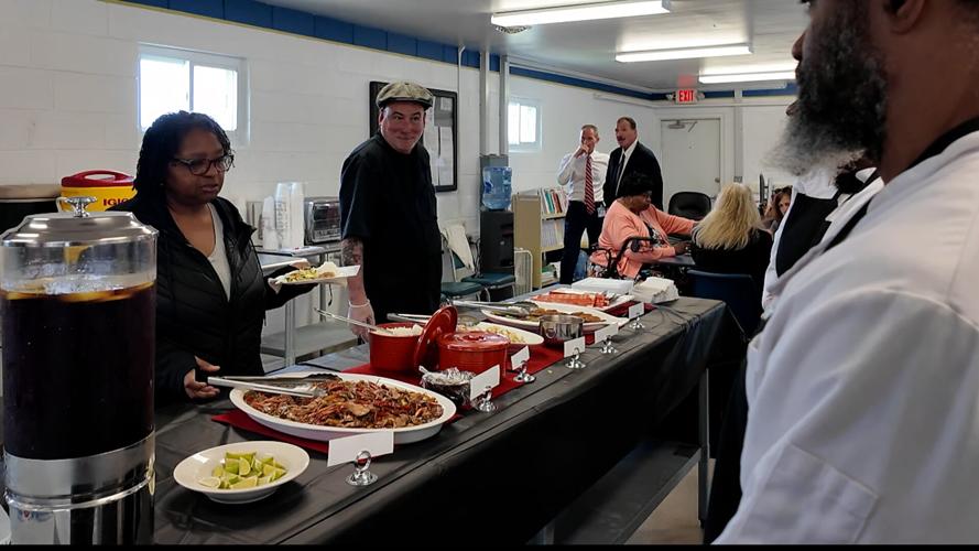 Inmates behind a table as people enjoy buffet style Thai cuisine that inmates prepared after graduating culinary program