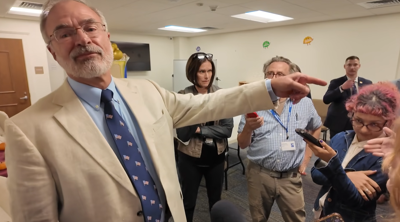 Andy Harris pointing towards the student journalist for an officer to assist him.