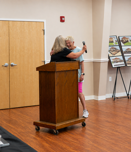 two women hug in celebration at a podium 