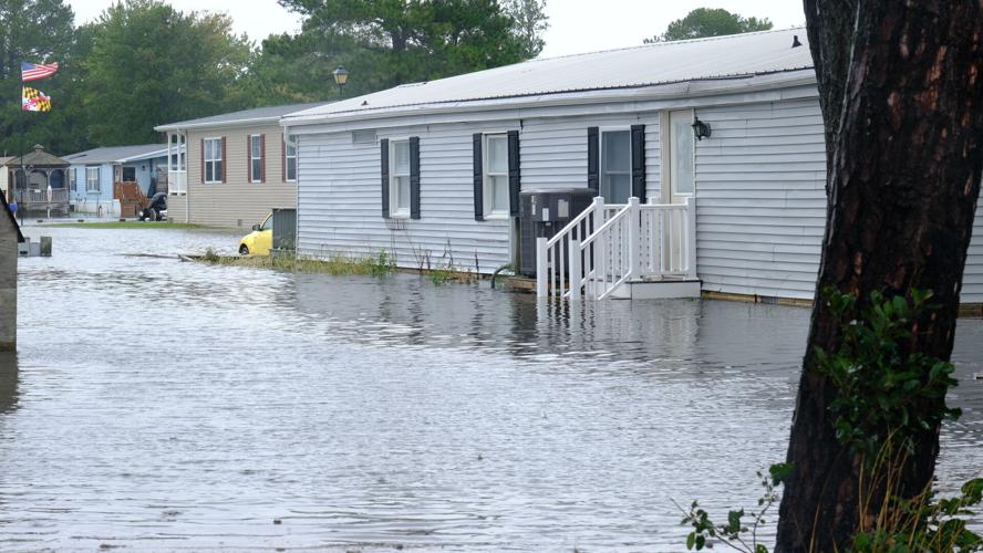 Water completely surrounds a manufactured home and covers all but the top step on an entrance porch.
