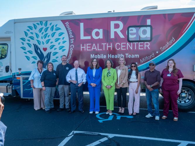 U.S. Sens. Chris Coons and Lisa Blunt Rochester and U.S. Rep. Sarah McBride with staff from La Red Health Center standing in front of a truck with the organization's logo.