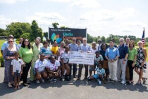 U.S. Senator Chris Van Hollen holding a check with community members for federal funding for the Flower Street Community Center.