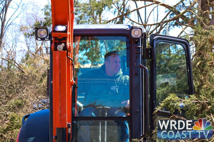 A cleanup volunteer working to move large branches and other debris.