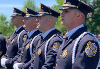 A line of men stand in uniform with the Delaware Department of Corrections patch on their sleeves.