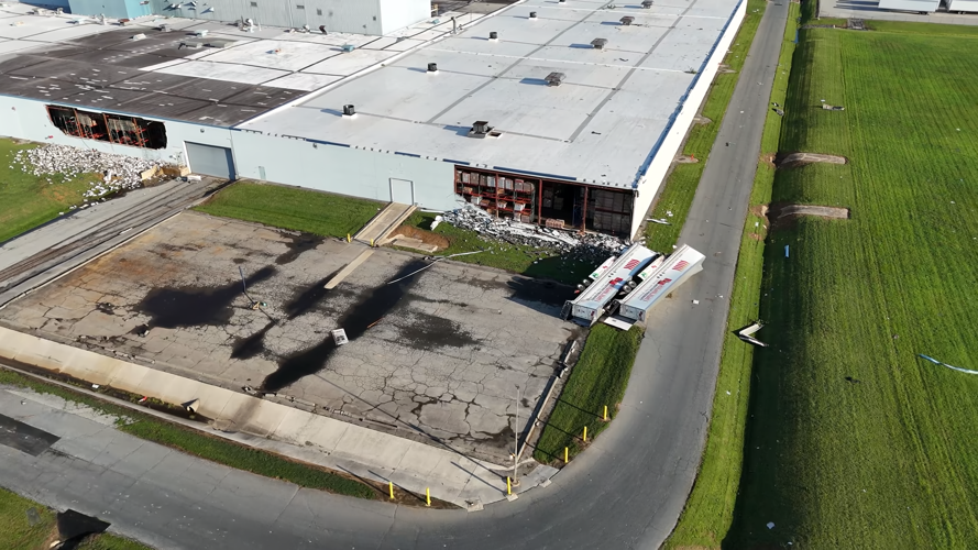 An aerial view of walls down on a large building and turned over tractor trailers.