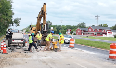 DELDOT crew members working on the closed lane of Route 1 with orange barrels marking the barrier.