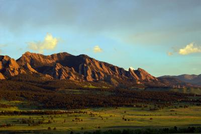 Landscape image of boulder flatirons and a lush field