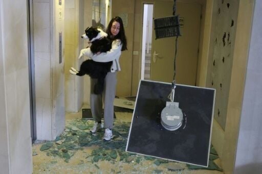 A woman carries her dog in a building damaged in an Iranian missile strike in Tel Aviv
