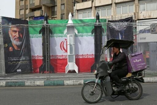 A motorist drives past mock Iranian missiles displayed in Tehran's Valiasr square on March 22