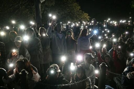 People turn on their mobile phones' flashlights to observe a minute's silence to reflect on the tragic Bondi Beach shooting attack before the New Year's Eve midnight fireworks display in Sydney