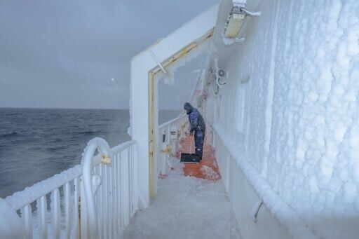 Voyage to the north: a crew member clears ice from the deck of Greenland's Sarfaq Ittuk ferry