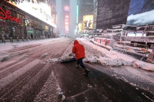 A worker clears a snow-covered street in Times Square early Monday in New York