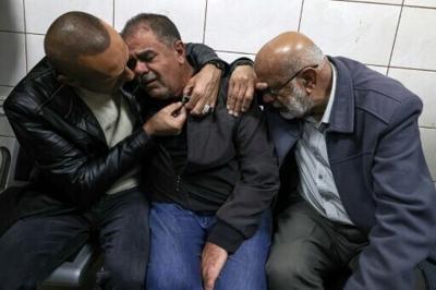 Palestinians try to console the father of Bahaa Abdel-Rahman Rashid at the nearby city of Nablus' Rafidia hospital